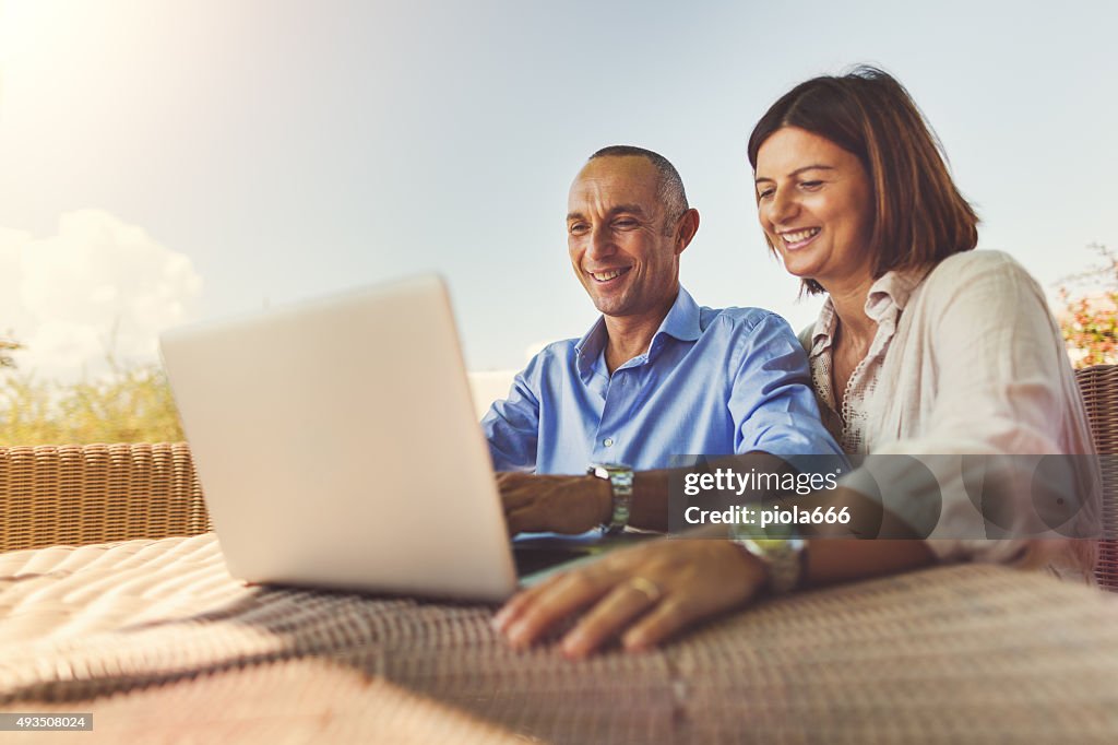 Mature couple planning vacation on laptop