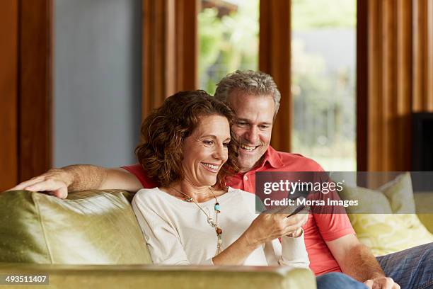 mature couple using mobile phone at home - adults on phone stock-fotos und bilder