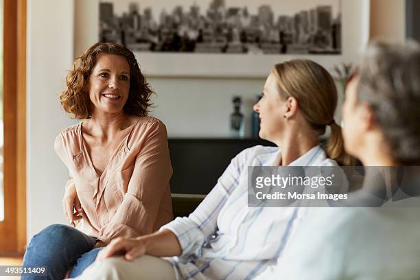 woman conversing with friends at home - kleine personengruppe stock-fotos und bilder