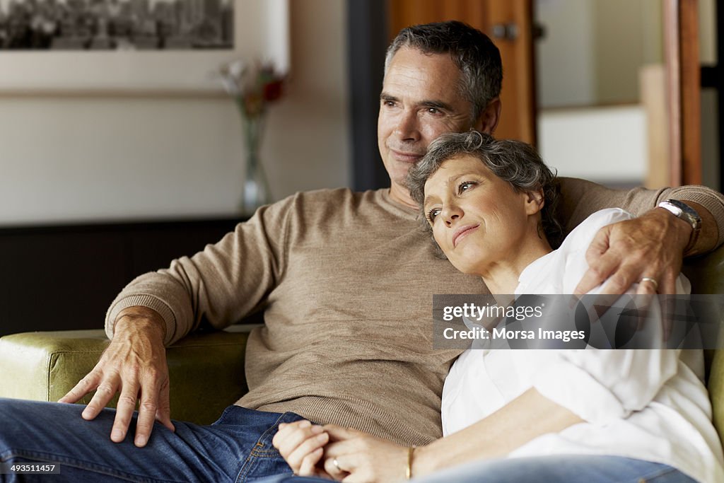 Thoughtful mature couple relaxing on sofa