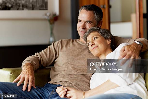 thoughtful mature couple relaxing on sofa - 55 couple ストックフォトと画像