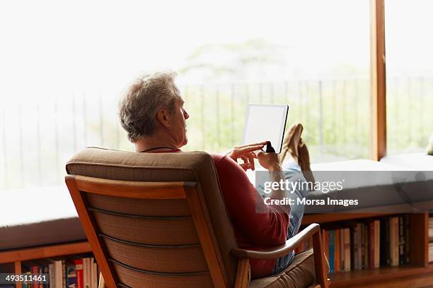 mature man using digital tablet at home - one mature man only stock pictures, royalty-free photos & images
