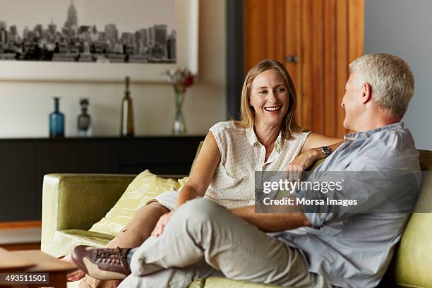 couple spending leisure time in living room - 40s couple stockfoto's en -beelden