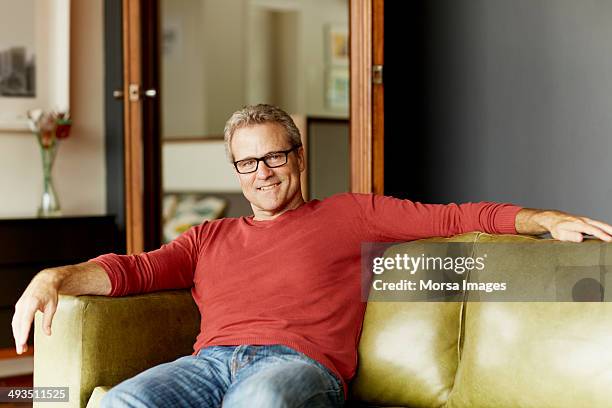 happy man relaxing on sofa - red sofa stock pictures, royalty-free photos & images