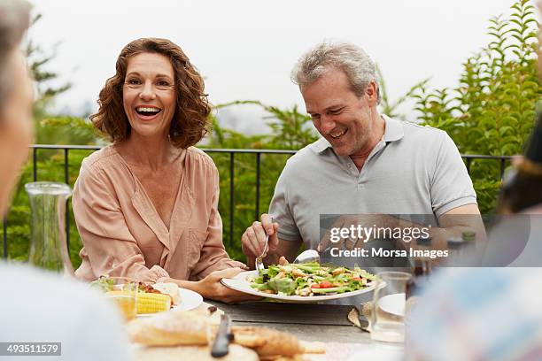 couple enjoying outdoor lunch with friends - frau 50 garten stock-fotos und bilder