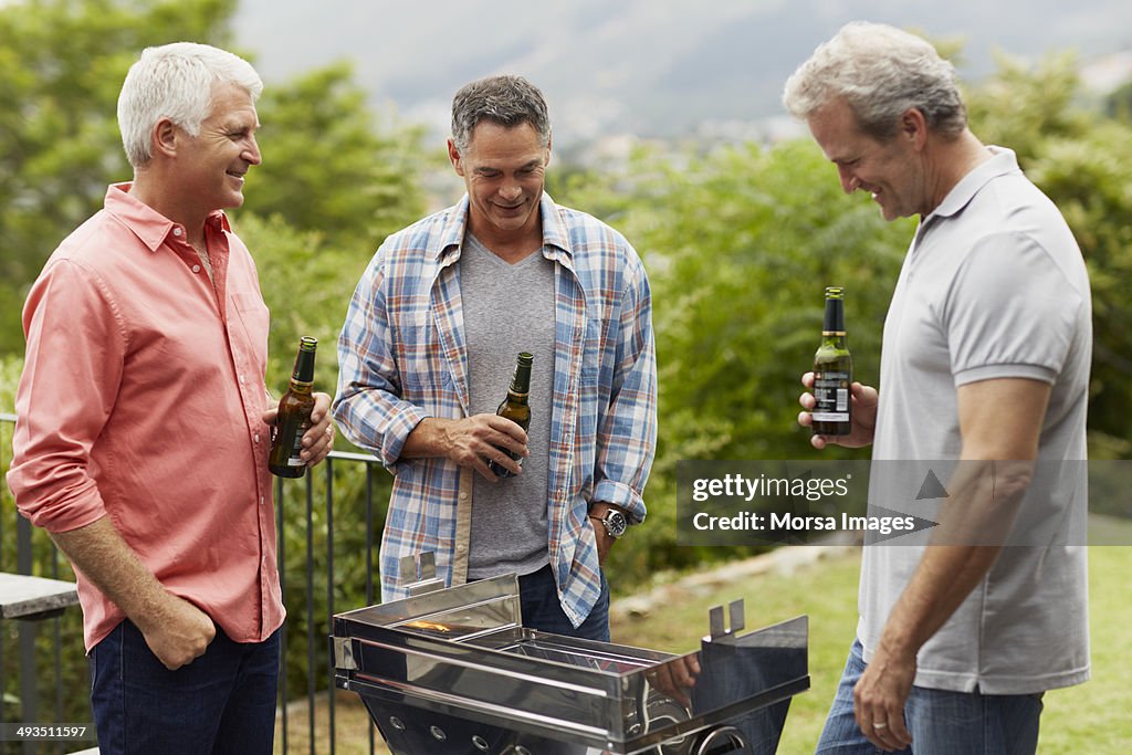 Mature friends having beer while barbecuing