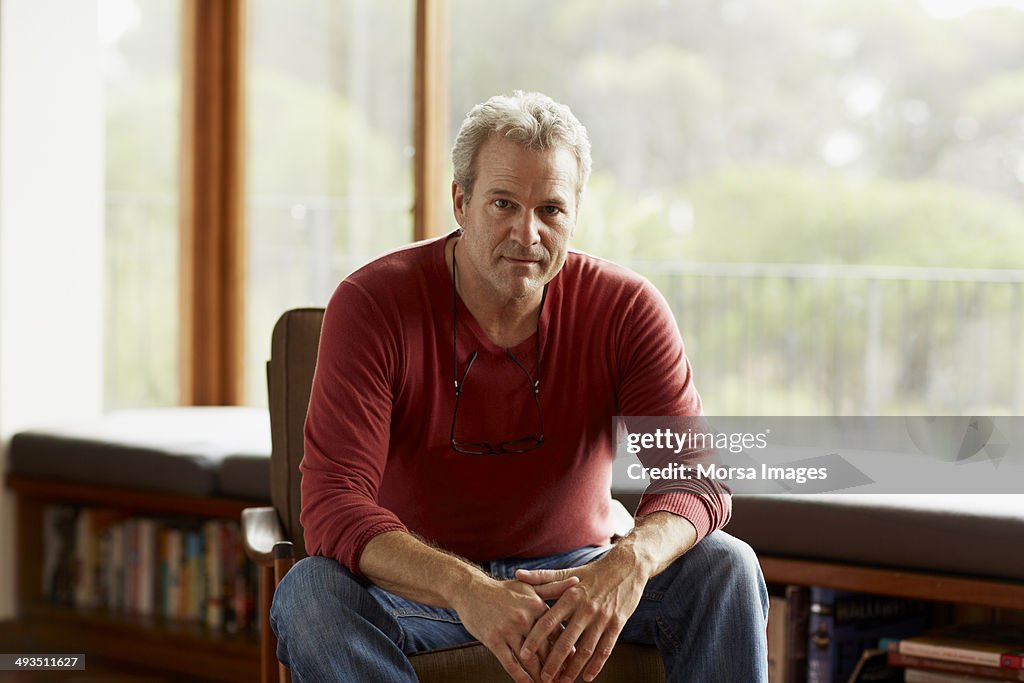 Confident man sitting on armchair at home