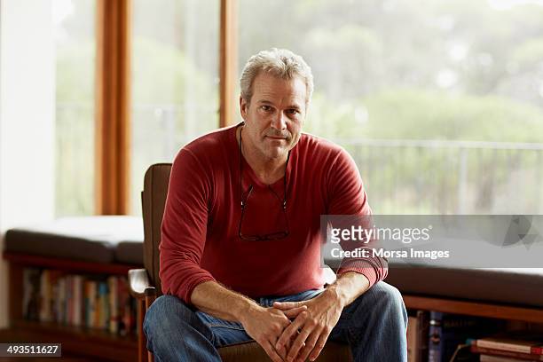 confident man sitting on armchair at home - mannelijk stockfoto's en -beelden