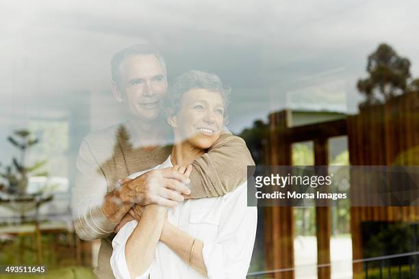 thoughtful couple looking through window - fenster stock-fotos und bilder