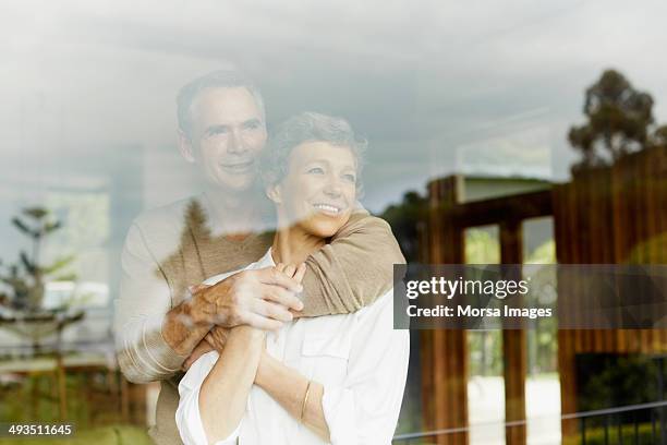 thoughtful couple looking through window - happy couple at home fotografías e imágenes de stock