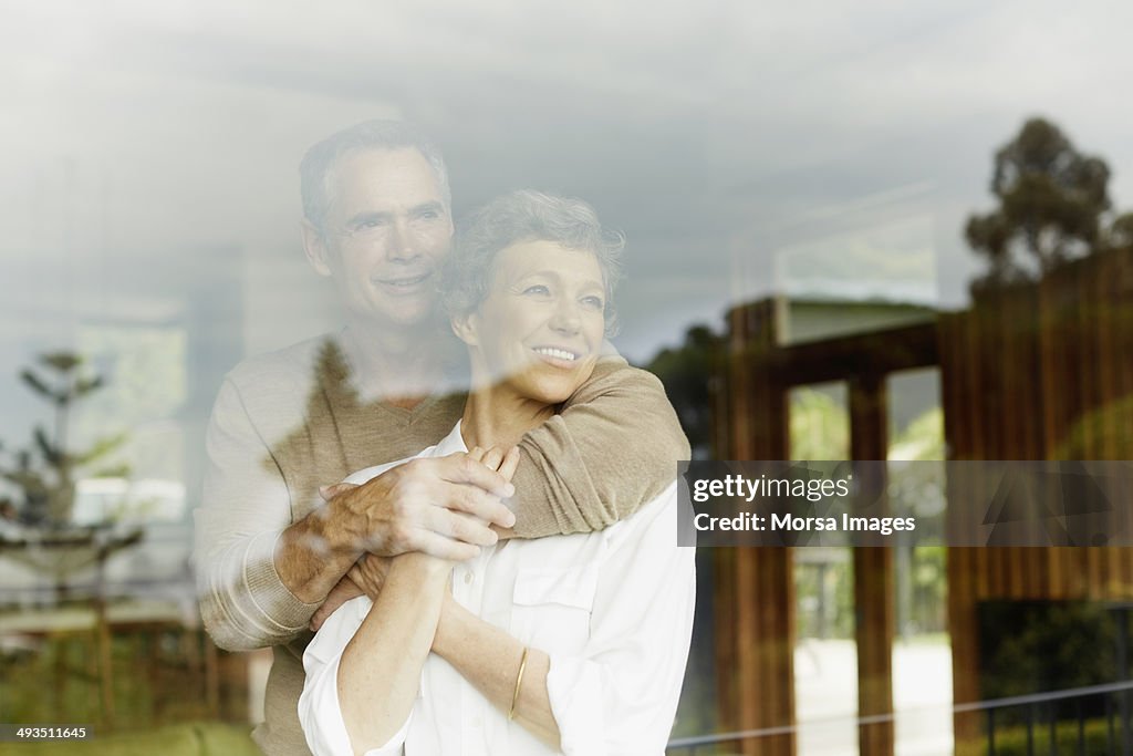 Thoughtful couple looking through window