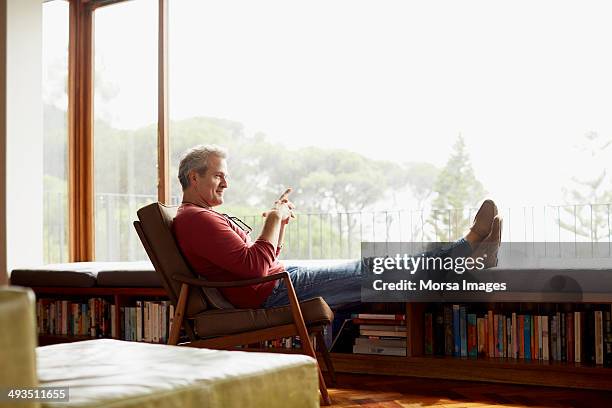 thoughtful mature man relaxing on armchair - sitting in a chair stockfoto's en -beelden