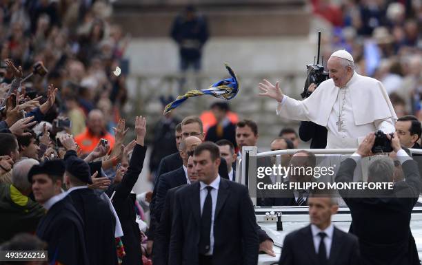 Pope Francis catches a scarf thrown by a worshipper as he greets the crowd from the popemobile before his weekly general audience at St Peter's...