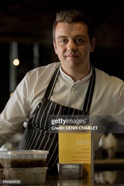 French head chef of the Grenouillère restaurant Alexandre Gauthier poses for a photograph along with a copy of the 2016 Gault and Millau restaurant...