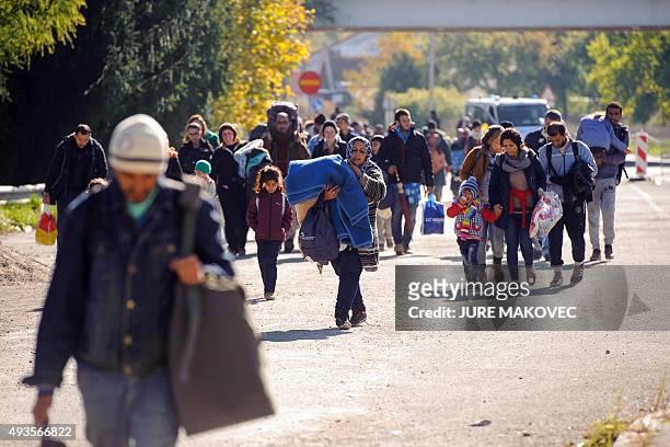 Migrants and asylum seekers walk to cross the Slovenian-Austrian border in Sentilj to continue their journey onto Spielfeld on October 21, 2015. Tens...