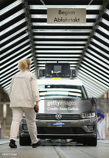 Worker walks towards a finished Volkswagen car at the end of the assembly line prior to a visit by Volkswagen Group Chairman Matthias Mueller and...