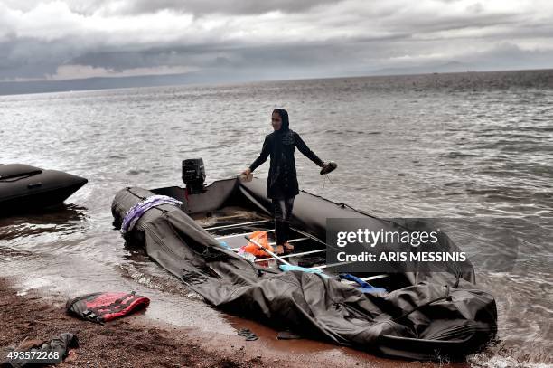 Young woman stands barefoot in a deflated dinghy after arriving with other refugees and migrants on the Greek island of Lesbos after crossing the...