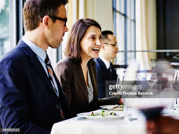 smiling businesswoman leading lunch meeting - conference dining table stockfoto's en -beelden