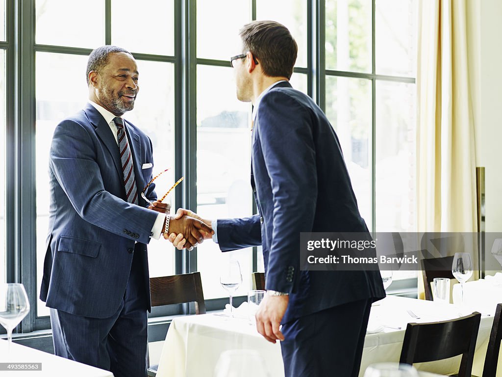 Two businessmen shaking hands at lunch meeting