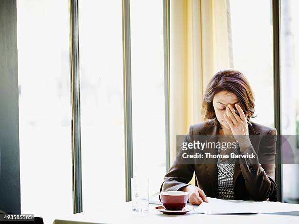 businesswoman at table with head resting on hand - self doubt ストックフォトと画像