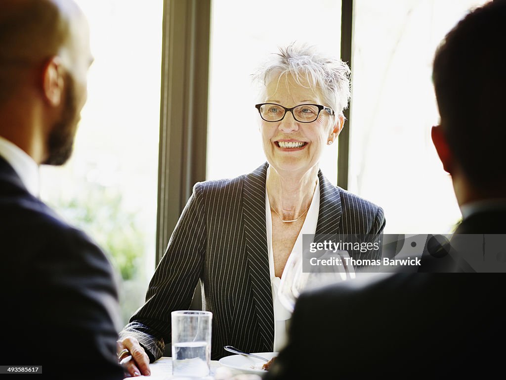 Smiling senior female executive at lunch meeting