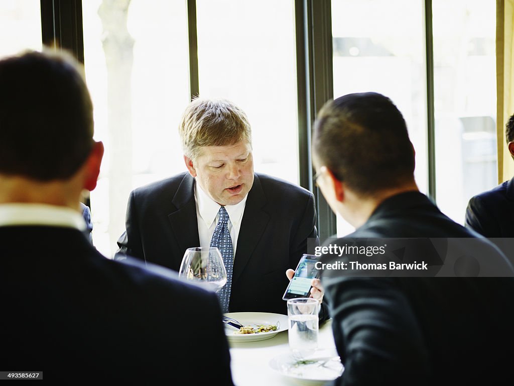 Businessman with smart phone at lunch meeting