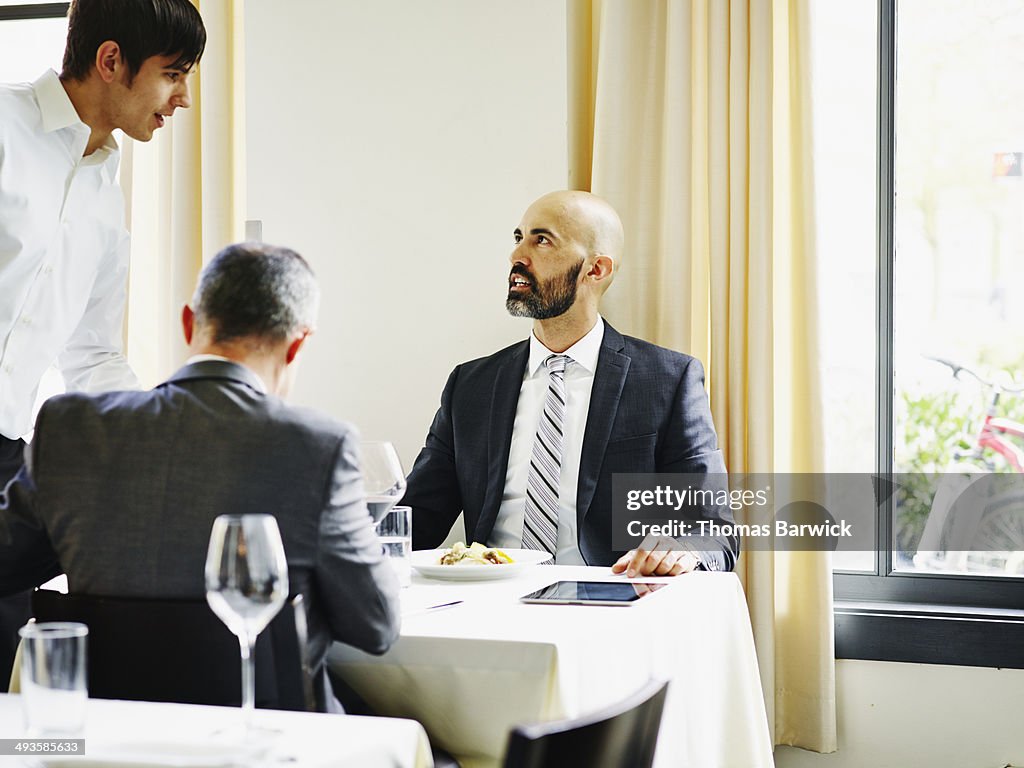 Two businessmen sitting at table in restaurant