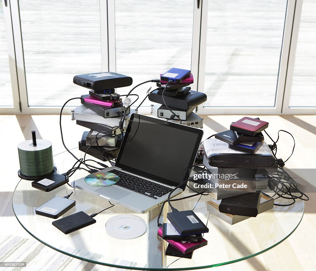 Laptop surrounded by hard drives and discs