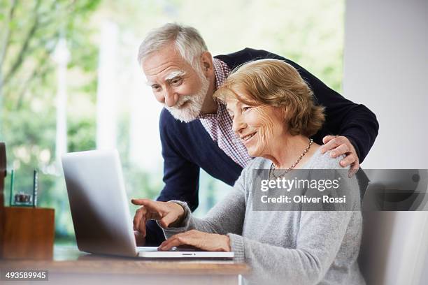 senior couple at home using laptop - senior women stock-fotos und bilder