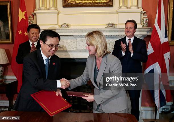 Britain's International Development Secretary Justine Greening and China's Minister of Commerce Gao Hucheng shake hands after signing an agreement as...