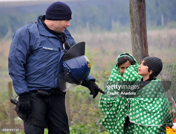 Serbian police talks to refugee children as the refugees who crossed the Macedonia - Serbia border try to reach Berkasovo town on the Serbia -...