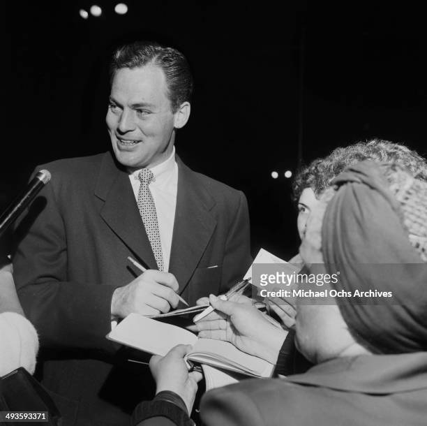 Actor John Agar signs autographs at the opening of Ice Capades in Los Angeles, California.