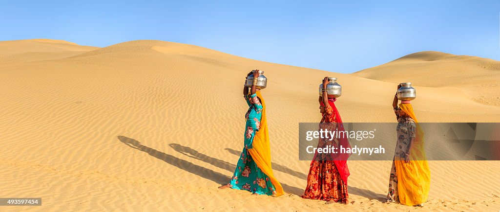 Indian women carrying on their heads water from local well