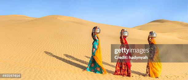 indian women carrying on their heads water from local well - woman in red sari stock pictures, royalty-free photos & images