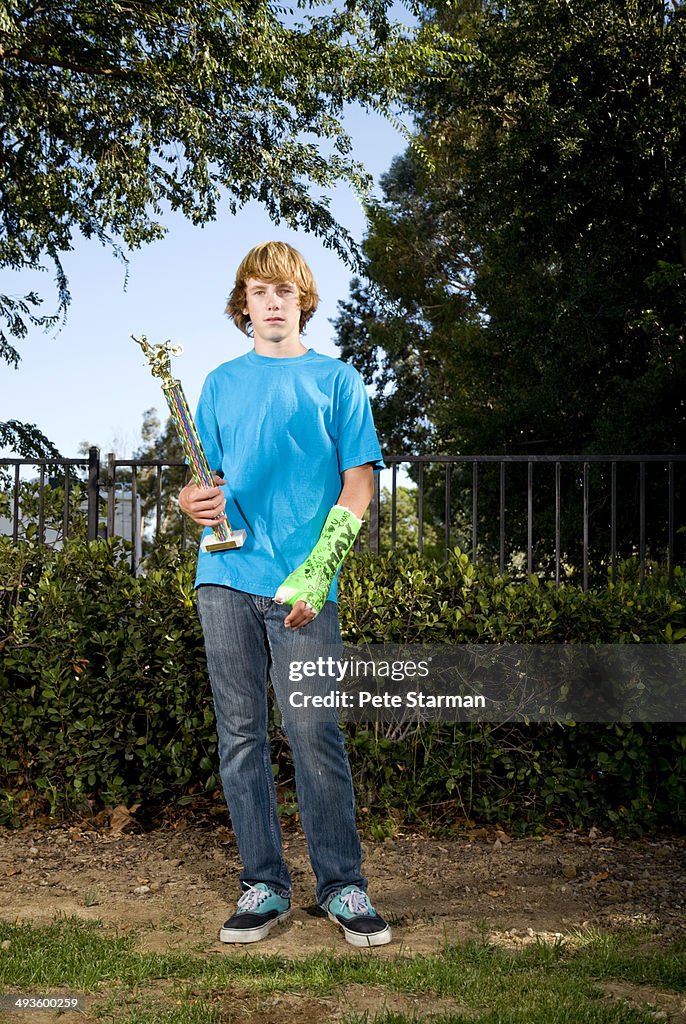 Teen with cast holding trophy