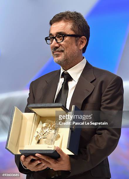 Director Nuri Bilge Ceylan poses on stage after being awarded with the Palme d'Or for the film 'Winter Sleep' on stage during the Closing Ceremony at...