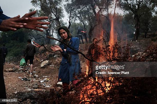 Migrants keep warm by a fire as they cope with the wet and cool weather while waiting to be processed at the increasingly overwhelmed Moria camp on...
