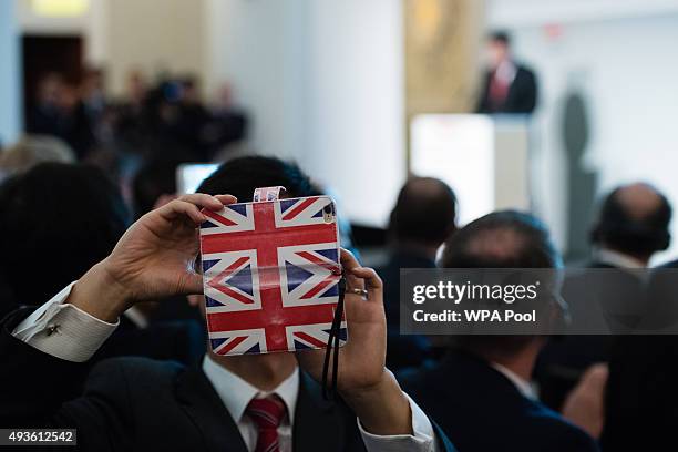 Summit attendee with a Union flag phone cover takes a selfie as the President of the People's Republic of China delivers a speech at the UK-China...