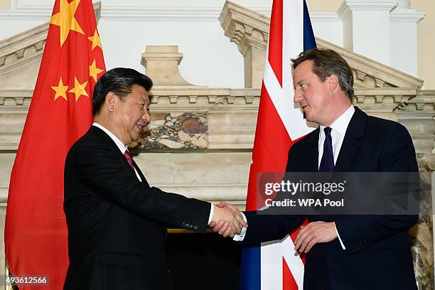 British Prime Minister David Cameron shakes hands with the President of the People's Republic of China Xi Jinping during a commercial contract...