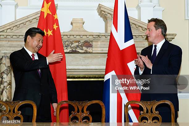 British Prime Minister David Cameron applauds next to the President of the People's Republic of China Xi Jinping during a commercial contract...