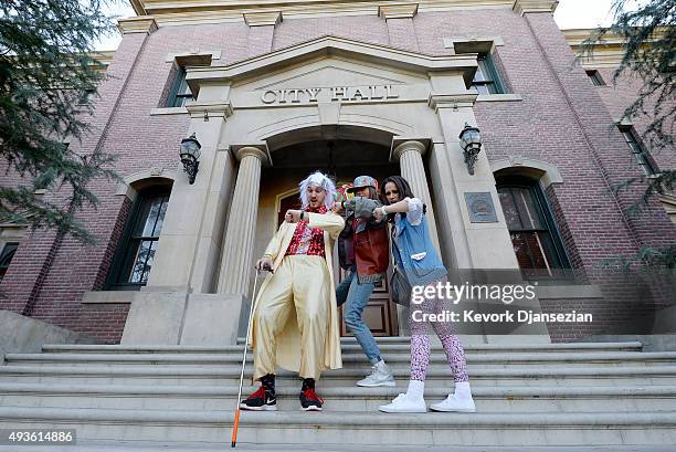 Mike Knell, dressed as the character Dr. Emmett Brown, Stephanie Knell and Jackie Peters pose on steps of Hill Valley Courthouse Square in the back...