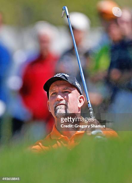 Marco Dawson watches his shot to the 18th green from a fairway sand trap during the third round of the 2014 Senior PGA Championship presented by...