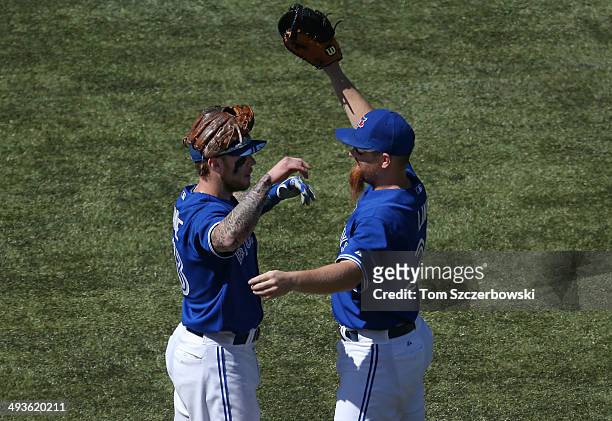 Brett Lawrie of the Toronto Blue Jays celebrates their victory with Adam Lind during MLB game action against the Oakland Athletics on May 24, 2014 at...