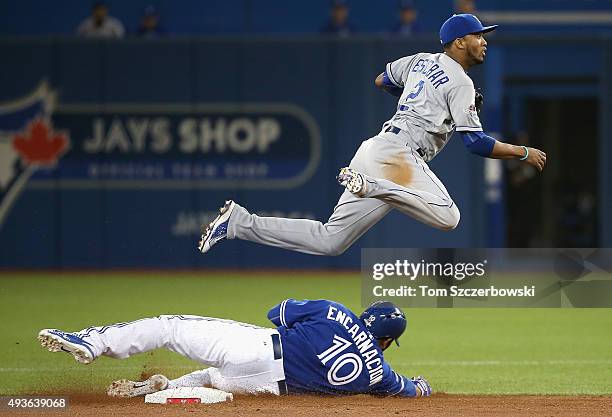 Alcides Escobar of the Kansas City Royals jumps over Edwin Encarnacion of the Toronto Blue Jays to turn a double play to end the fourth inning during...