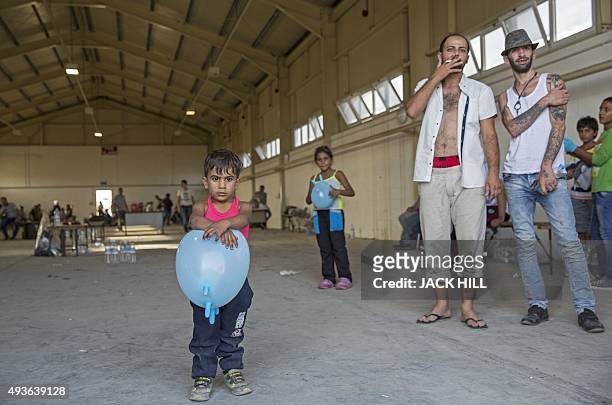 Migrants stand in a warehouse after coming ashore at a British airbase in Akrotiri on October 21, 2015. More than 100 migrants crowded into two boats...