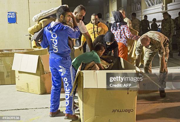 Air force personnel help prepare beds for migrants at a warehouse after coming ashore at a British airbase in Akrotiri on October 21, 2015. More than...