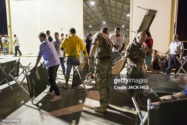 Air force personnel help prepare beds for migrants at a warehouse after coming ashore at a British airbase in Akrotiri on October 21, 2015. More than...