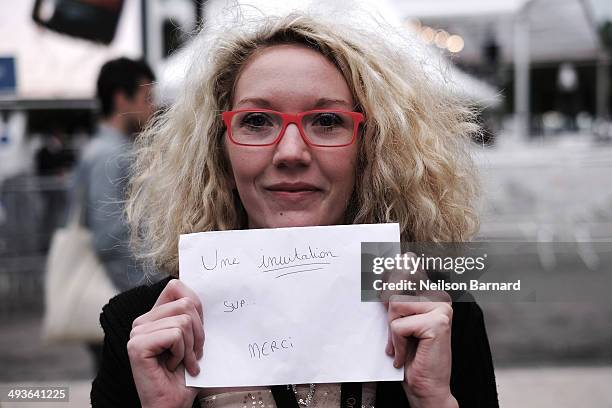 Film fans wait outside the Palais des Festivals holding signs in the hope of getting a ticket to one of the many films showing during the 67th Annual...