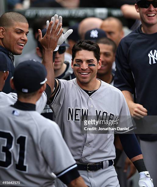 Jacoby Ellsbury of the New York Yankees is greeted by teammates in the dugout after hitting a solo home run in the 10th inning against the Chicago...