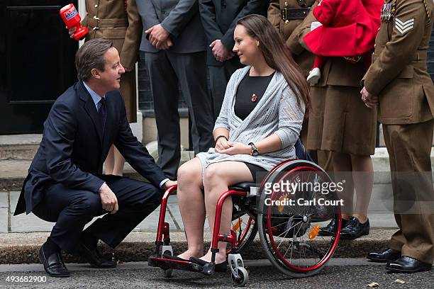 Prime Minister David Cameron chats with former Royal Artillery soldier Emma Pack after buying his remembrance poppy in Downing Street on October 22,...